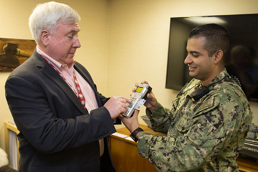 Fiscal Service Director and sailor look at Point of Sale Device